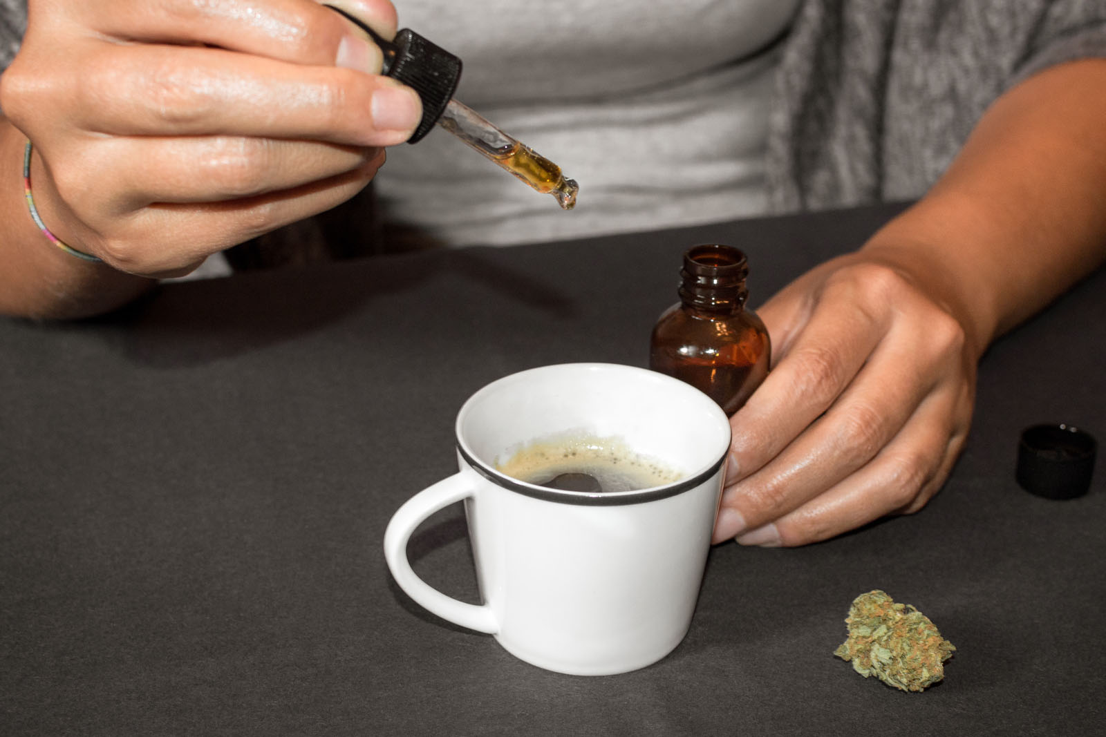 Pouring CBD tincture in a coffee cup, natural medicine made with marijuana. 
